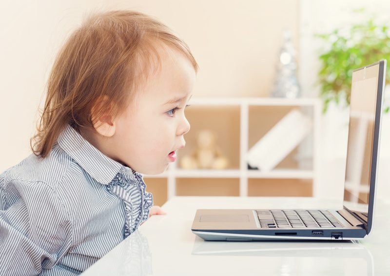 Amazed toddler girl watching something astonishing on her laptop